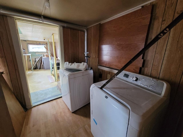 washroom featuring light wood-type flooring, washing machine and dryer, and wood walls