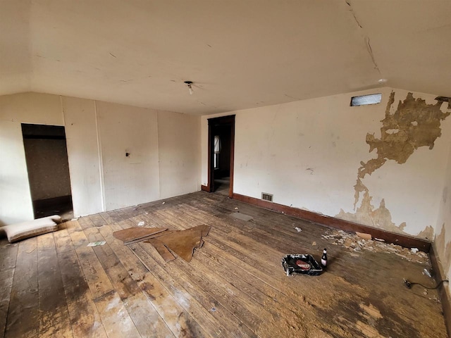 spare room featuring wood-type flooring and lofted ceiling