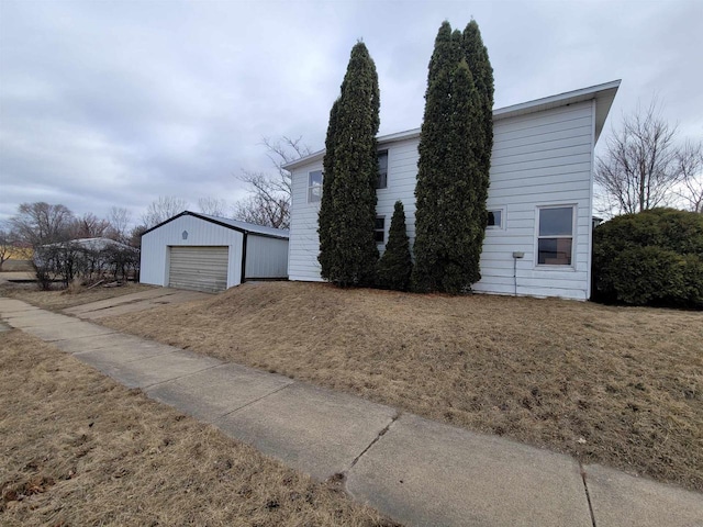 view of front of property featuring a garage, an outbuilding, and a front lawn