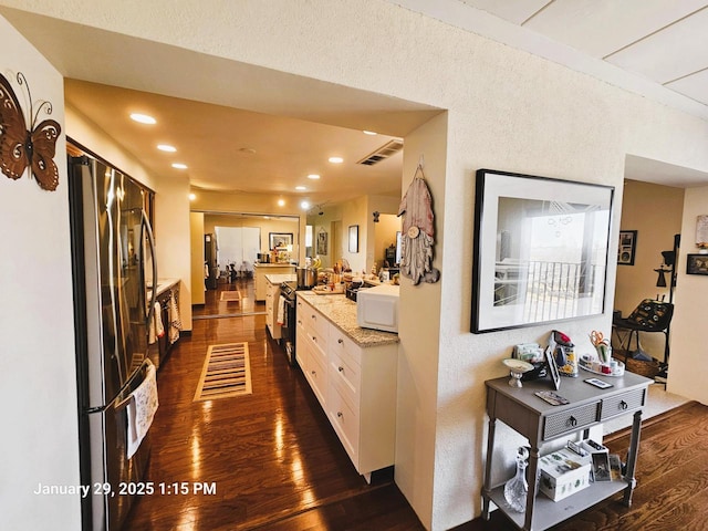 kitchen with stainless steel range with electric cooktop, light stone counters, fridge, dark hardwood / wood-style flooring, and white cabinets