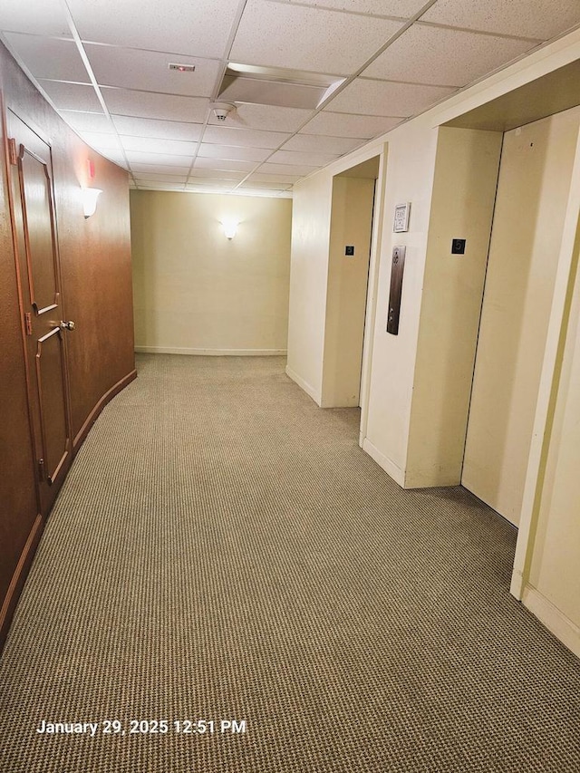 basement with dark colored carpet, a paneled ceiling, and elevator