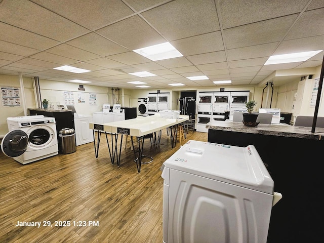 kitchen with hardwood / wood-style flooring, a drop ceiling, and washer and clothes dryer