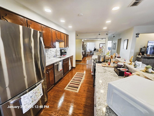 kitchen featuring appliances with stainless steel finishes, sink, dark hardwood / wood-style flooring, decorative backsplash, and track lighting