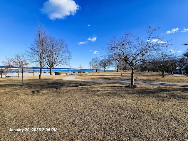 exterior space featuring a view of the beach, a lawn, and a water view