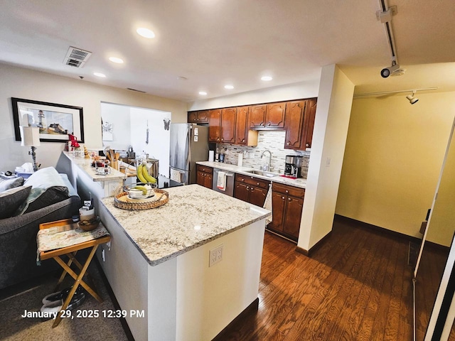 kitchen featuring rail lighting, sink, backsplash, dark hardwood / wood-style flooring, and stainless steel appliances