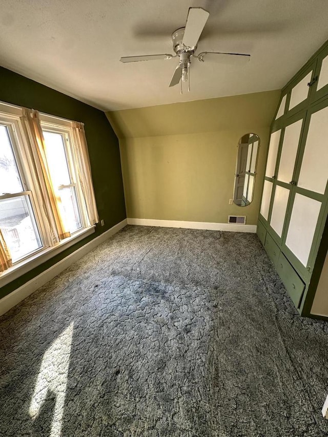 carpeted empty room with vaulted ceiling and ceiling fan