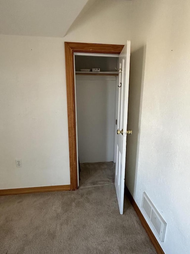 unfurnished bedroom featuring vaulted ceiling, dark carpet, and a closet