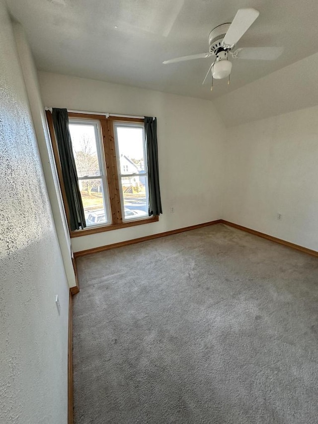 empty room with ceiling fan, carpet flooring, and vaulted ceiling