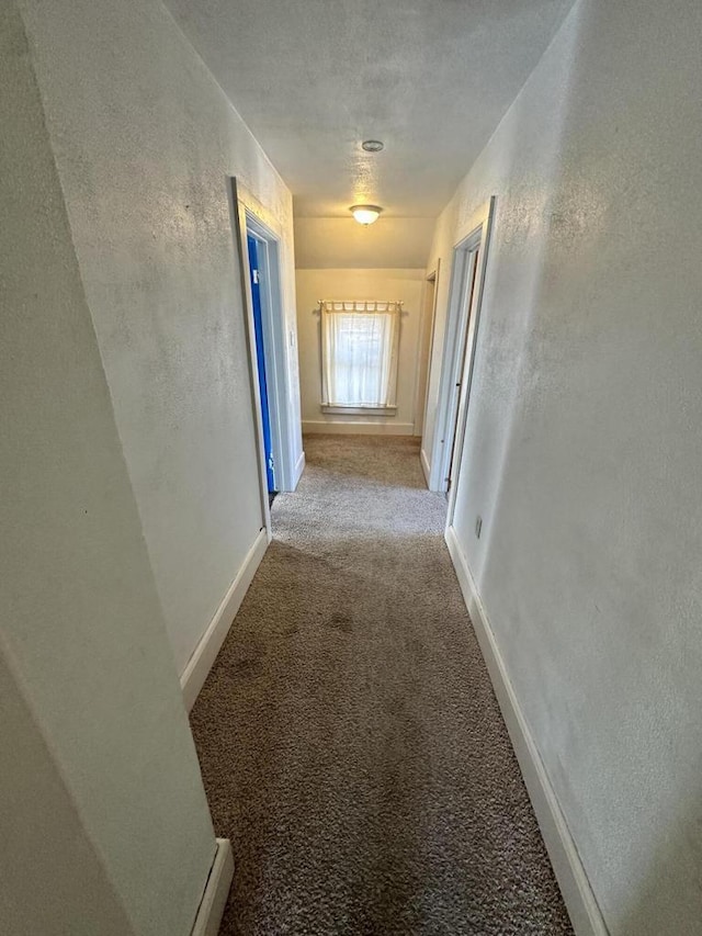 hall featuring light colored carpet and a textured ceiling