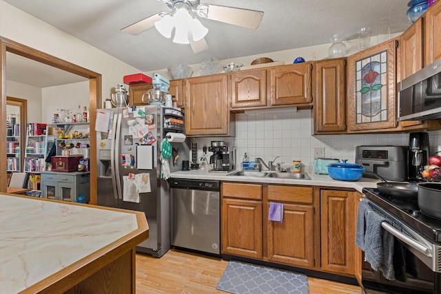 kitchen with appliances with stainless steel finishes, light hardwood / wood-style floors, sink, and decorative backsplash