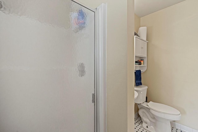 bathroom featuring a shower with shower door and toilet