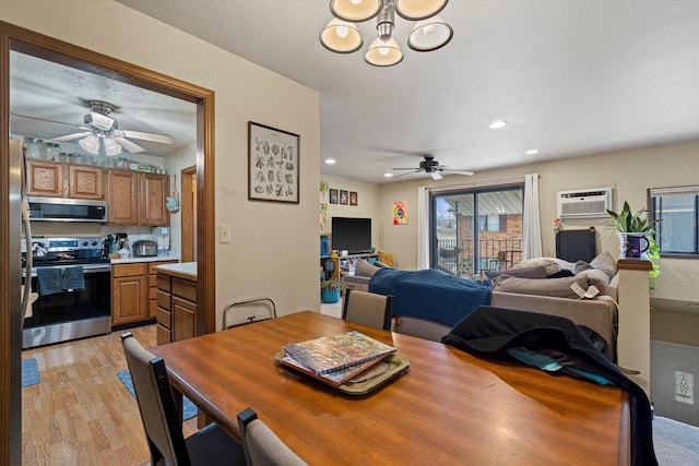 dining area with an AC wall unit, ceiling fan with notable chandelier, and light wood-type flooring