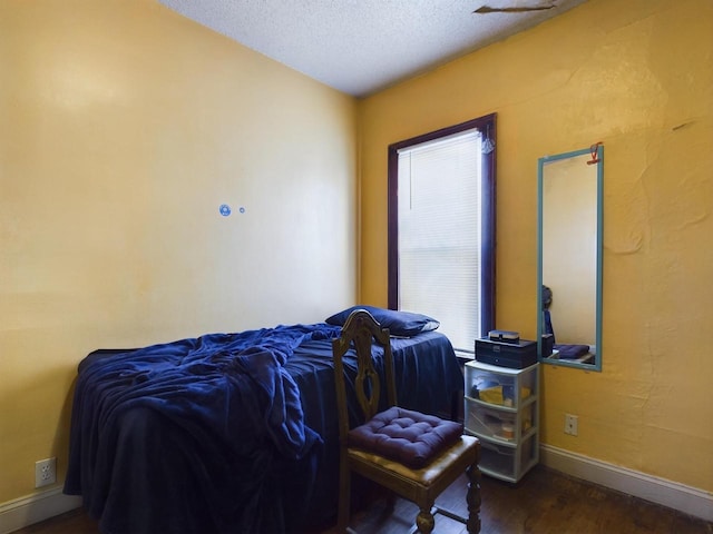 bedroom with dark hardwood / wood-style floors and a textured ceiling