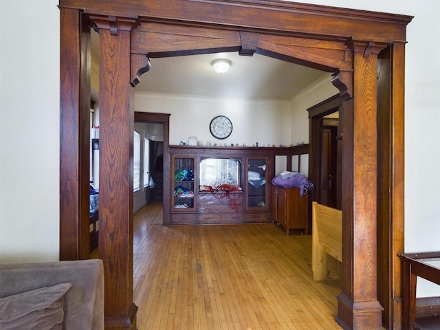 corridor with ornamental molding and light wood-type flooring