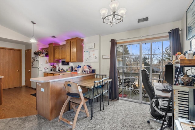 kitchen featuring decorative light fixtures, lofted ceiling, white fridge, kitchen peninsula, and an inviting chandelier