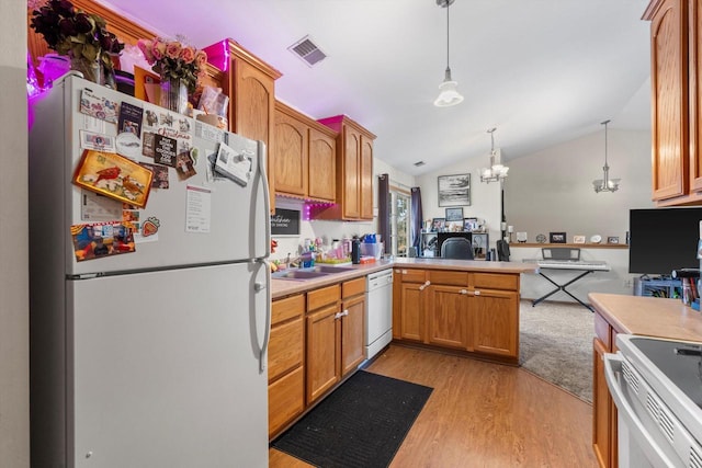 kitchen with pendant lighting, white appliances, light hardwood / wood-style floors, vaulted ceiling, and kitchen peninsula