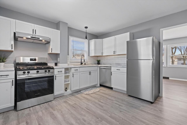 kitchen featuring sink, stainless steel appliances, light hardwood / wood-style floors, white cabinets, and decorative light fixtures