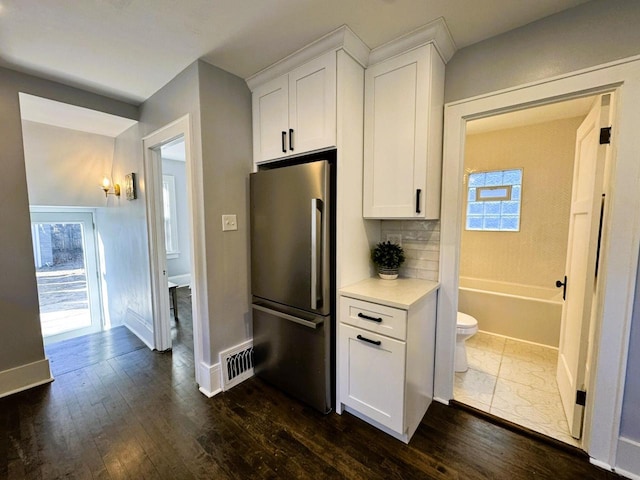 kitchen featuring white cabinets, a wealth of natural light, stainless steel fridge, and decorative backsplash