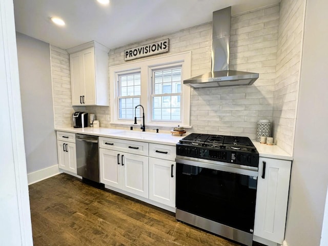 kitchen featuring tasteful backsplash, white cabinetry, stainless steel dishwasher, wall chimney range hood, and gas range oven