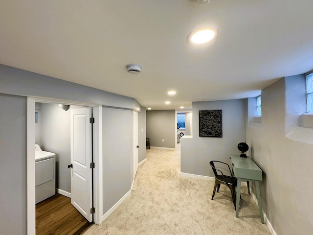 hall with washer / dryer and light colored carpet