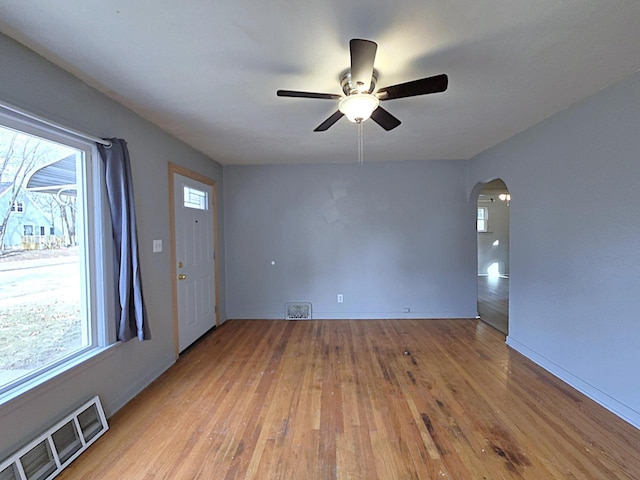 empty room with a wealth of natural light, light hardwood / wood-style flooring, and ceiling fan