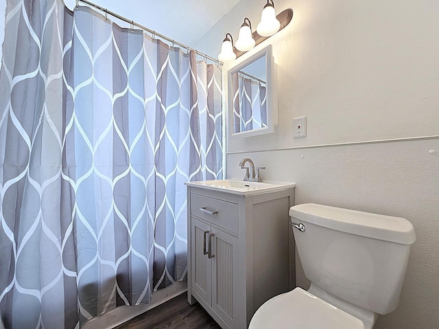 bathroom with walk in shower, vanity, toilet, and wood-type flooring