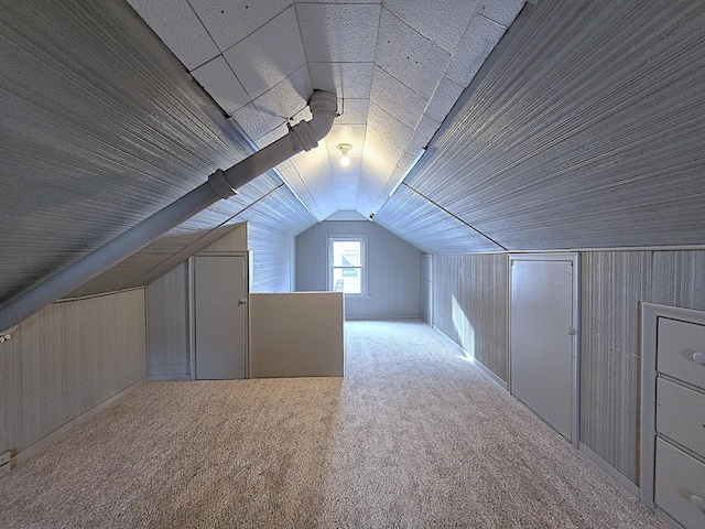 additional living space with light colored carpet, vaulted ceiling, and wood walls