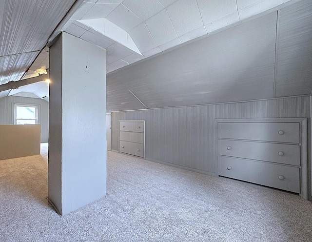 bonus room with light colored carpet, lofted ceiling, and wood walls