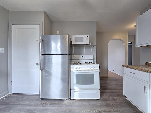 kitchen featuring stone counters, white appliances, wood-type flooring, and white cabinets