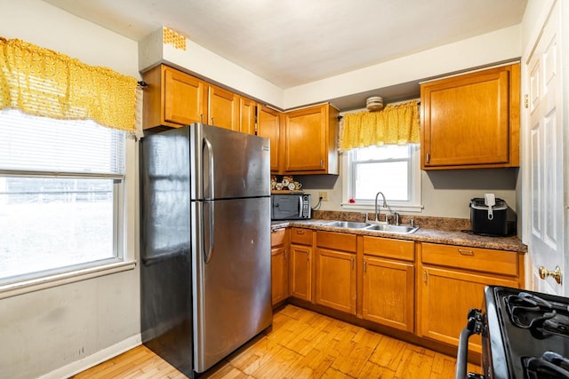 kitchen with sink, light hardwood / wood-style flooring, and black appliances