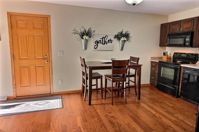 kitchen with dark brown cabinetry, light wood-type flooring, and black appliances