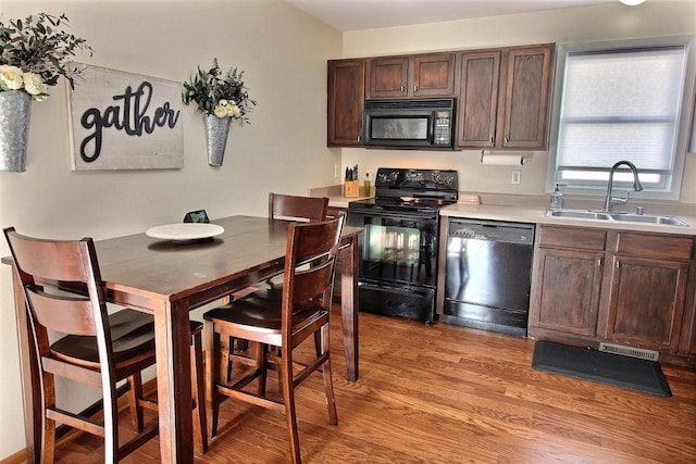 kitchen featuring sink, dark brown cabinets, black appliances, and light hardwood / wood-style floors