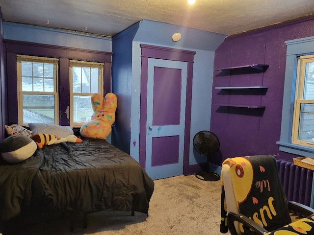 bedroom with radiator heating unit, carpet flooring, and a textured ceiling