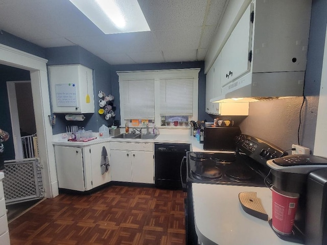 kitchen featuring dark parquet flooring, sink, black appliances, white cabinets, and a drop ceiling