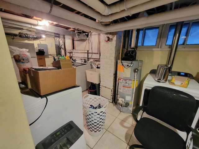 basement featuring water heater, washing machine and dryer, sink, and light tile patterned flooring