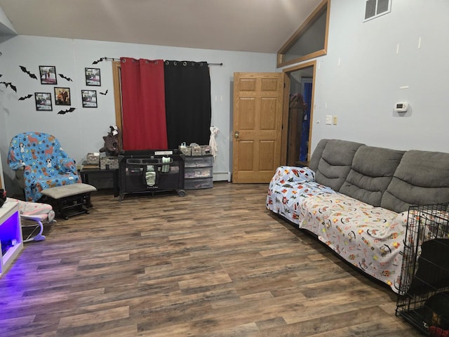 living room featuring dark hardwood / wood-style floors, vaulted ceiling, and a baseboard heating unit