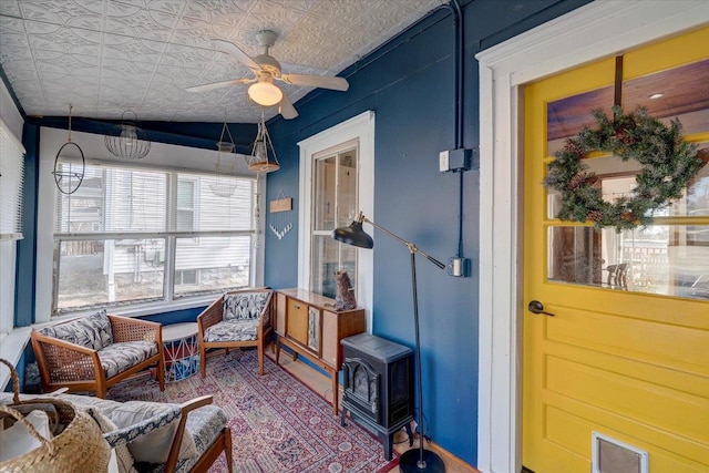 sunroom / solarium featuring a wood stove and ceiling fan