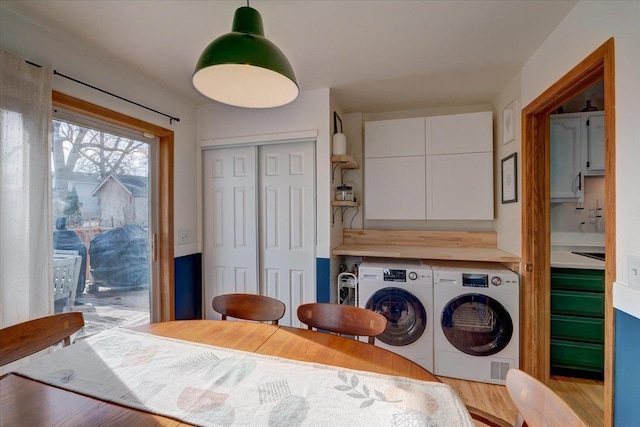 laundry room featuring cabinets, sink, separate washer and dryer, and light hardwood / wood-style floors