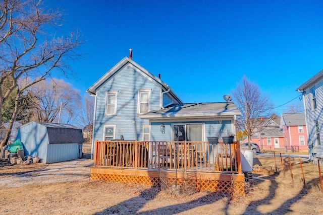 rear view of house with a wooden deck and a storage shed