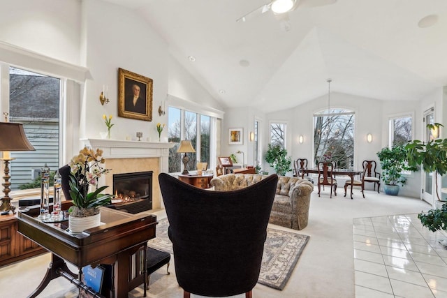 carpeted living room with a premium fireplace, ceiling fan, and high vaulted ceiling