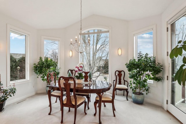 carpeted dining area with lofted ceiling, a healthy amount of sunlight, and a chandelier