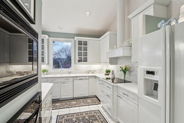 kitchen with white cabinets, backsplash, light tile patterned floors, black appliances, and wall chimney exhaust hood