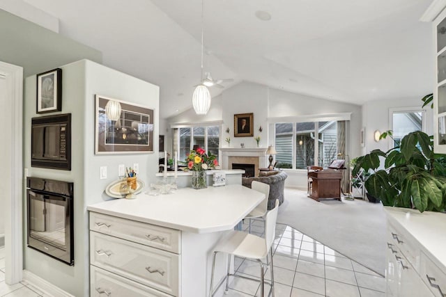 kitchen with white cabinetry, lofted ceiling, a kitchen breakfast bar, light tile patterned floors, and black appliances