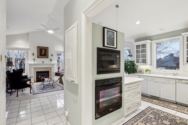 kitchen featuring light tile patterned flooring, white cabinetry, vaulted ceiling, hanging light fixtures, and black appliances