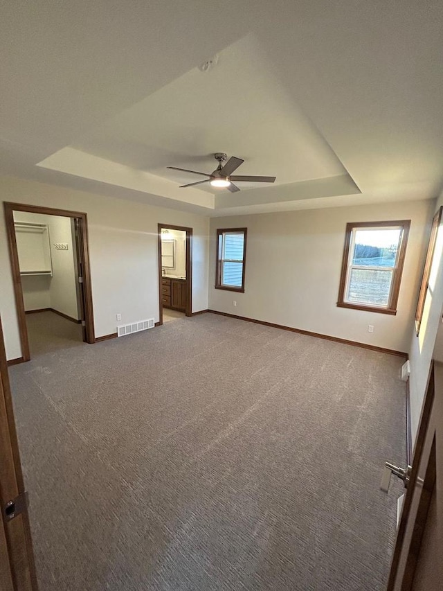 carpeted spare room with ceiling fan and a raised ceiling