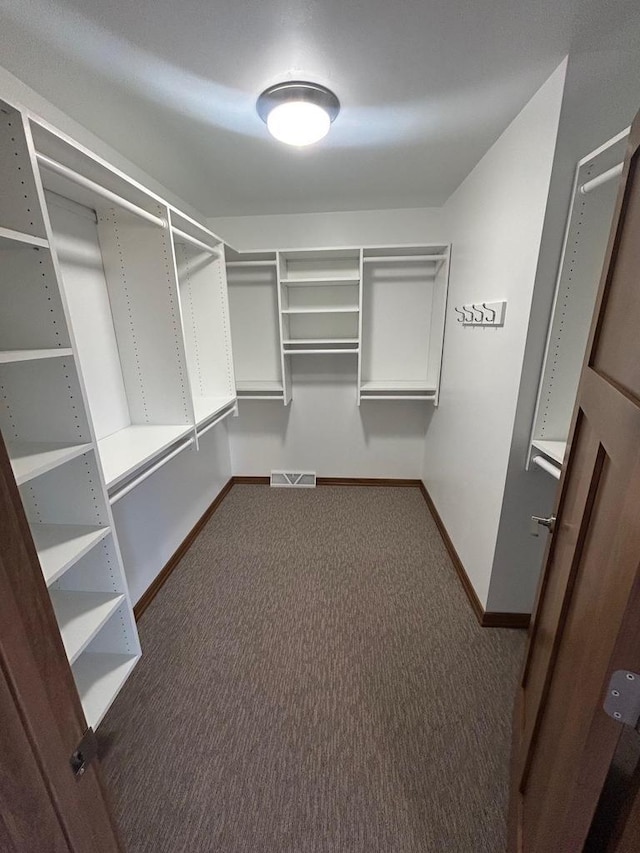 walk in closet with dark carpet