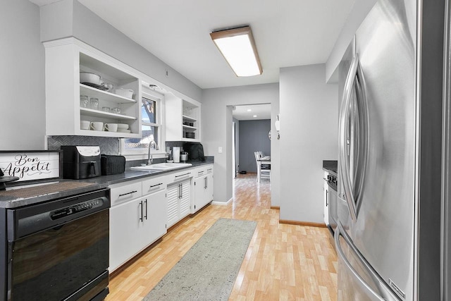 kitchen featuring sink, light hardwood / wood-style flooring, stainless steel refrigerator, black dishwasher, and white cabinets