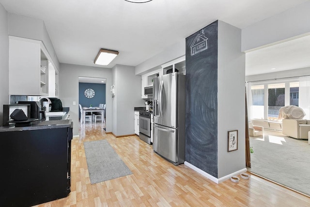 kitchen with stainless steel appliances, white cabinetry, sink, and light hardwood / wood-style floors