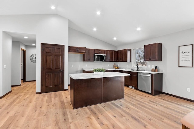 kitchen featuring appliances with stainless steel finishes, high vaulted ceiling, sink, a center island, and light hardwood / wood-style flooring