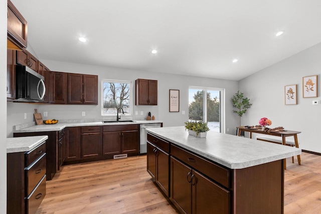 kitchen with light hardwood / wood-style floors, appliances with stainless steel finishes, a center island, and sink